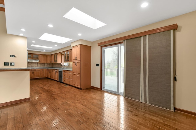 kitchen with dishwasher, dark hardwood / wood-style flooring, sink, and a skylight