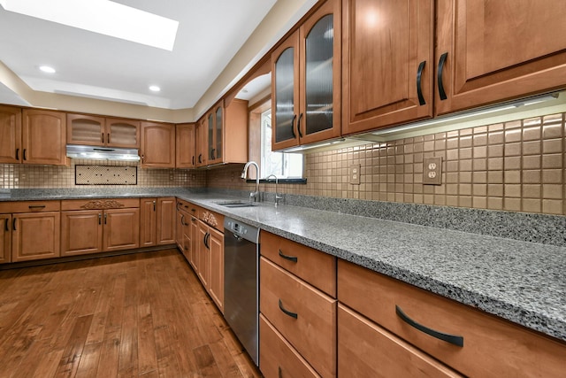 kitchen with a skylight, sink, dark hardwood / wood-style flooring, stainless steel dishwasher, and decorative backsplash