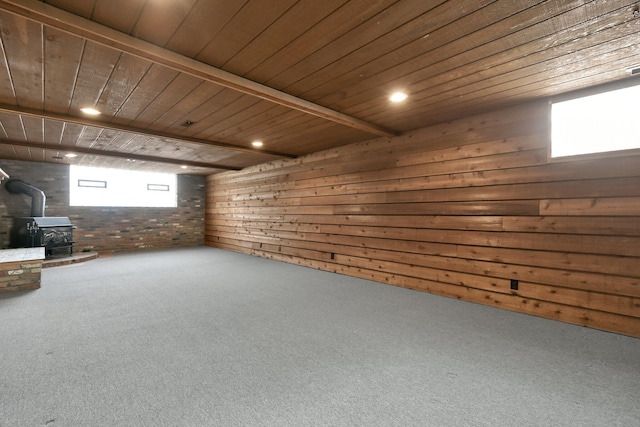 basement with carpet floors, a wood stove, and wooden ceiling