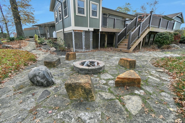 back of property with a fire pit and a wooden deck