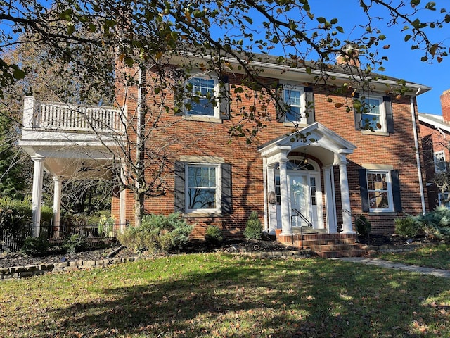 view of front of house with a balcony and a front yard