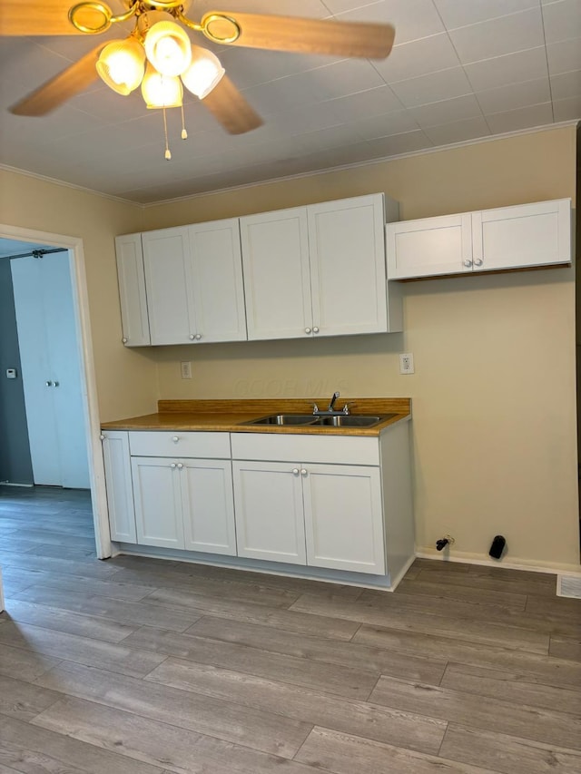 kitchen featuring white cabinetry, sink, ceiling fan, and light wood-type flooring