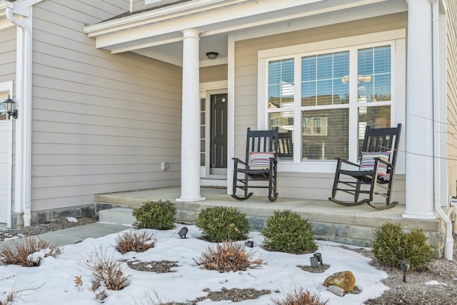 snow covered property entrance featuring a porch