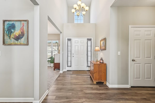 entrance foyer with a towering ceiling, dark wood-type flooring, and a chandelier