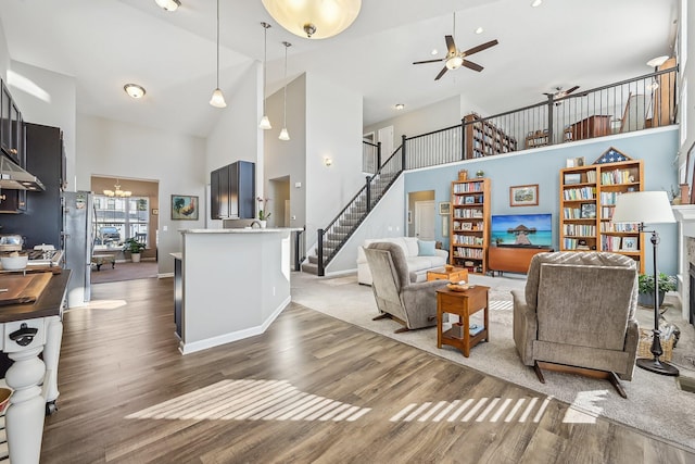 living room featuring dark wood-type flooring, ceiling fan with notable chandelier, and high vaulted ceiling