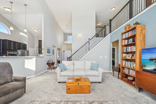 living room with washer / dryer, carpet flooring, an inviting chandelier, and high vaulted ceiling