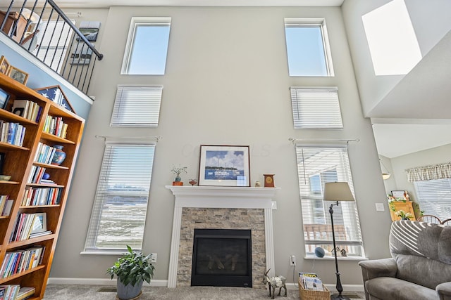 living room featuring a high ceiling, plenty of natural light, carpet floors, and a fireplace