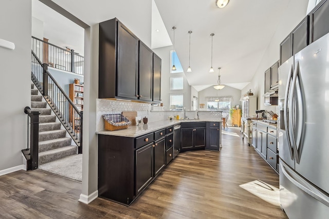 kitchen with sink, light stone counters, decorative light fixtures, appliances with stainless steel finishes, and dark hardwood / wood-style flooring