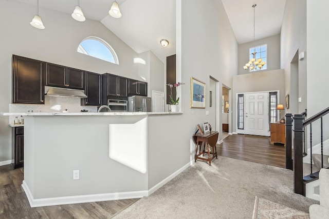 kitchen featuring a high ceiling, decorative light fixtures, stainless steel appliances, and kitchen peninsula