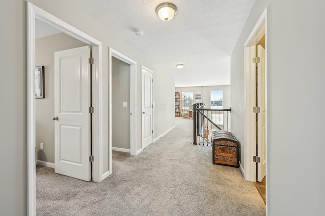 corridor featuring light carpet and a textured ceiling