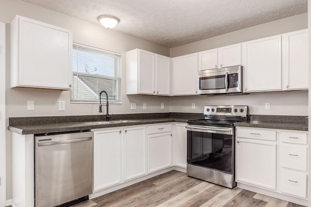 kitchen featuring sink, white cabinetry, stainless steel appliances, and light hardwood / wood-style flooring