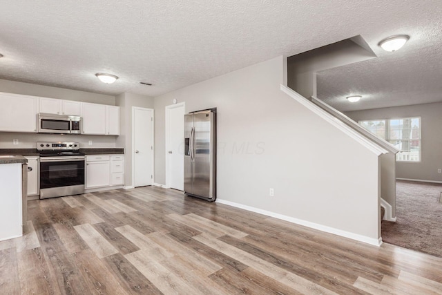 kitchen featuring light hardwood / wood-style flooring, white cabinets, a textured ceiling, and appliances with stainless steel finishes