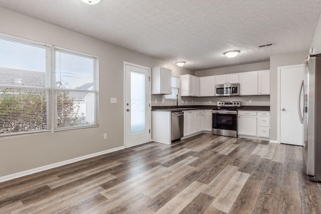 kitchen with wood-type flooring, white cabinetry, and appliances with stainless steel finishes