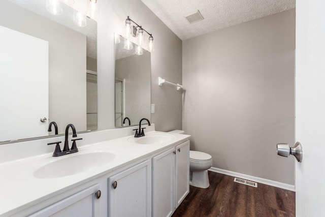 bathroom featuring hardwood / wood-style floors, vanity, a textured ceiling, and toilet