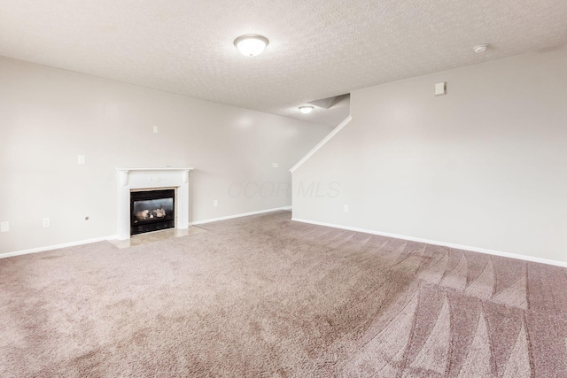 unfurnished living room with a textured ceiling, carpet floors, and a fireplace