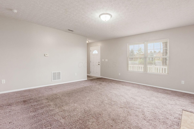 carpeted empty room with a textured ceiling