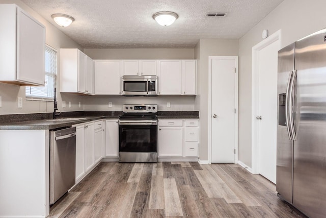 kitchen featuring white cabinets, sink, hardwood / wood-style floors, and appliances with stainless steel finishes