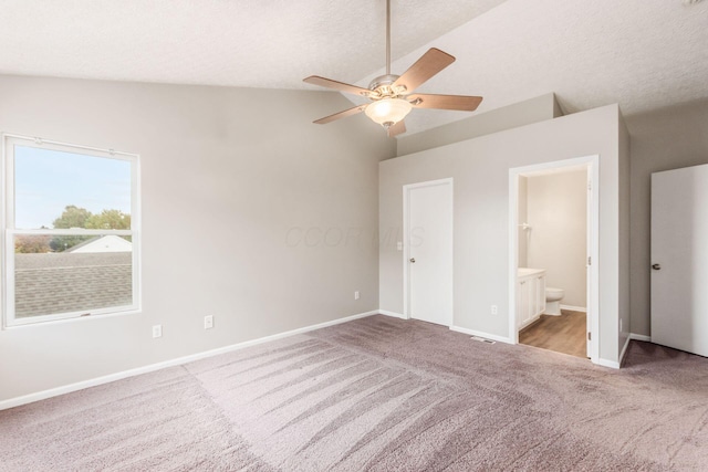 unfurnished bedroom with light carpet, ensuite bath, a textured ceiling, ceiling fan, and lofted ceiling