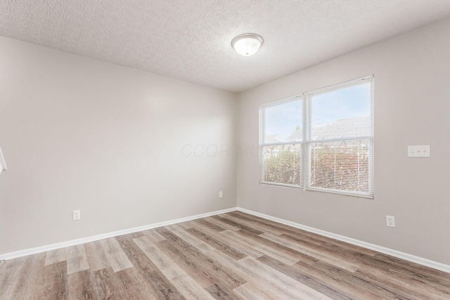 spare room featuring a textured ceiling and light wood-type flooring