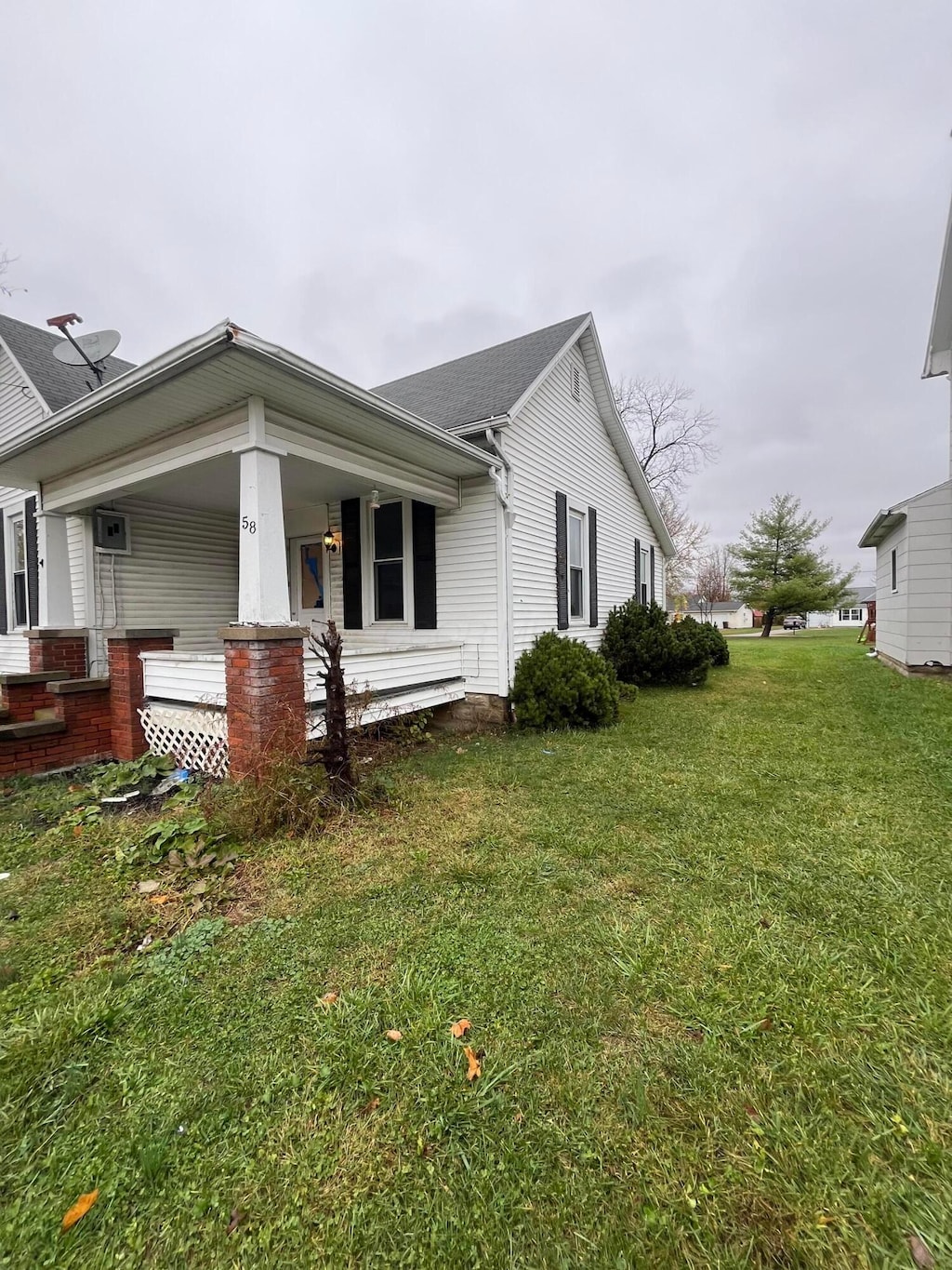 view of side of property featuring covered porch and a yard