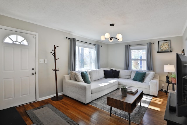 living room featuring dark wood-type flooring, a healthy amount of sunlight, a textured ceiling, and an inviting chandelier