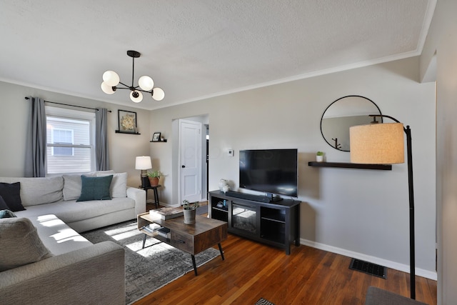 living room with a textured ceiling, a notable chandelier, dark hardwood / wood-style flooring, and crown molding