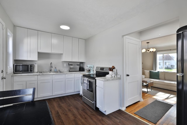 kitchen featuring dark wood-type flooring, white cabinets, hanging light fixtures, sink, and appliances with stainless steel finishes