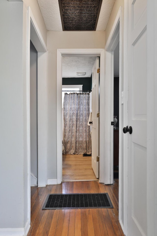 hallway with hardwood / wood-style floors and a textured ceiling