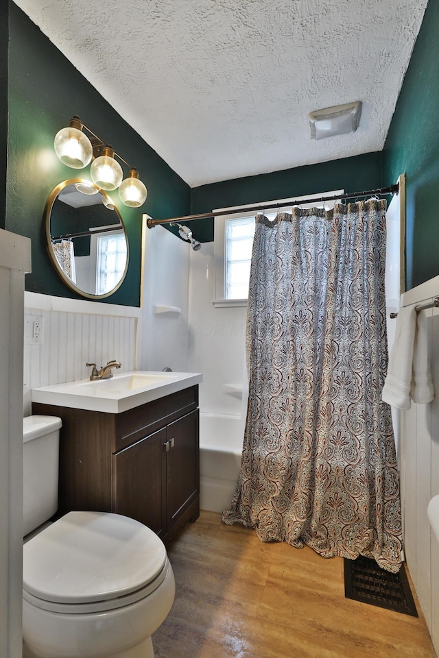 full bathroom featuring hardwood / wood-style floors, vanity, toilet, shower / bathtub combination with curtain, and a textured ceiling