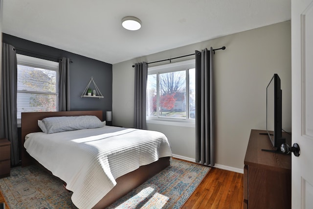 bedroom featuring multiple windows and dark hardwood / wood-style floors