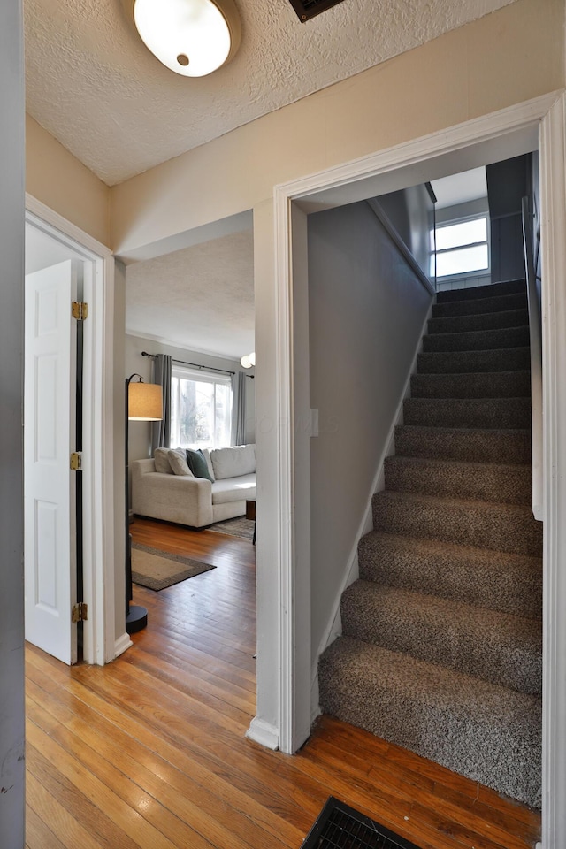 staircase featuring wood-type flooring and a textured ceiling