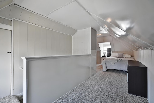 unfurnished bedroom featuring wood walls, carpet floors, and lofted ceiling