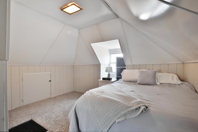 carpeted bedroom featuring wood walls and vaulted ceiling