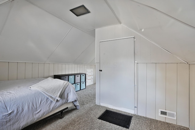 carpeted bedroom with wood walls and vaulted ceiling