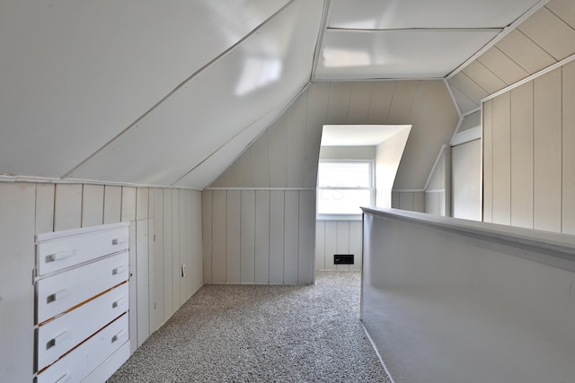 additional living space featuring carpet, wood walls, and lofted ceiling