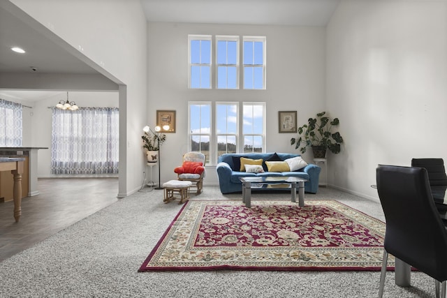 living room featuring carpet, a towering ceiling, and a chandelier