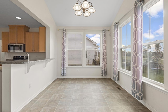 kitchen with kitchen peninsula, lofted ceiling, a breakfast bar area, and a notable chandelier