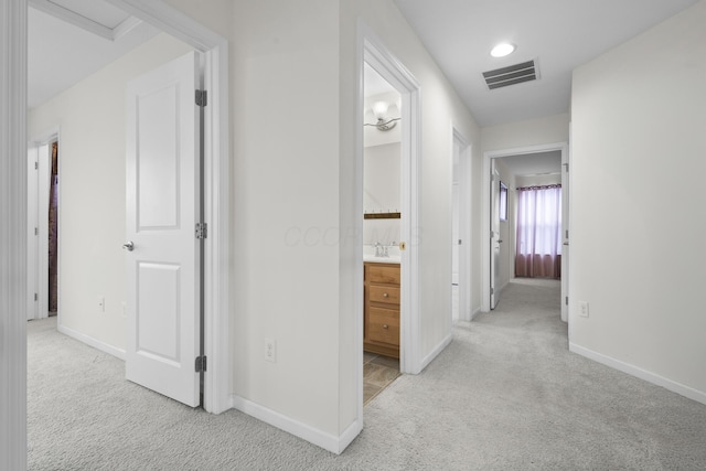 hall with light carpet and sink