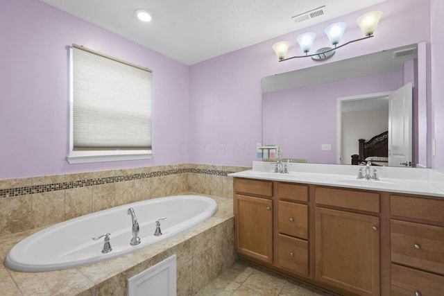 bathroom with tiled bath, tile patterned flooring, and vanity