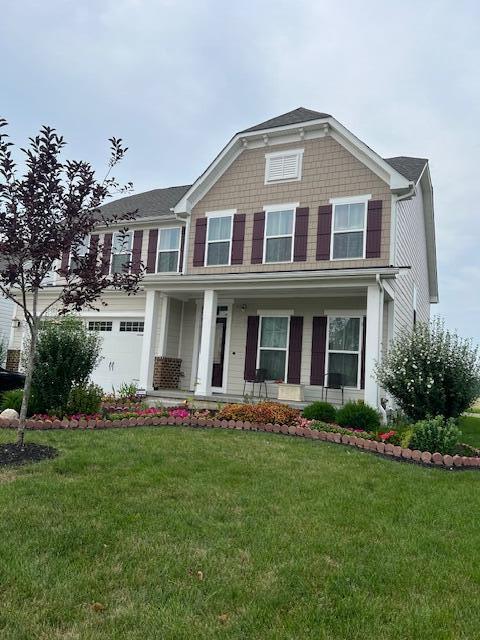 view of front facade featuring a porch, a garage, and a front lawn