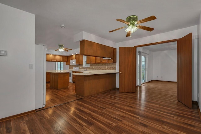 kitchen with kitchen peninsula, decorative backsplash, dark hardwood / wood-style flooring, white appliances, and ceiling fan