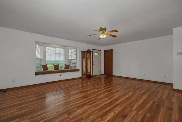 interior space with a textured ceiling, ceiling fan, and dark wood-type flooring