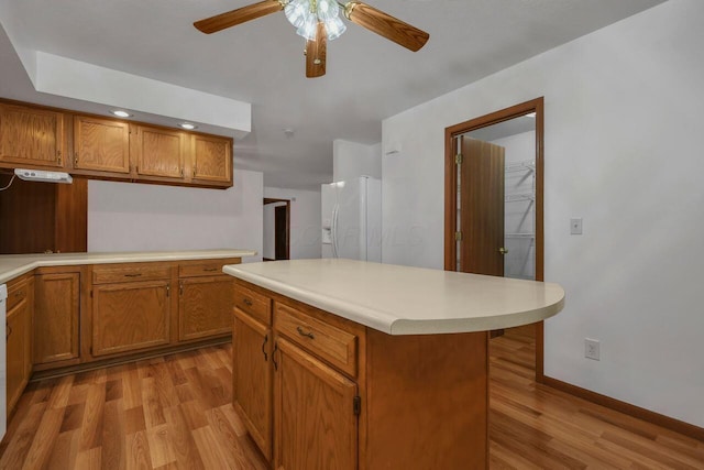 kitchen featuring white appliances, brown cabinetry, and light wood finished floors