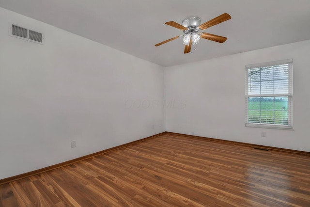 unfurnished room featuring ceiling fan, wood finished floors, visible vents, and baseboards