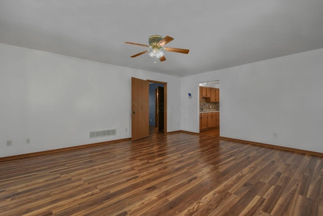 unfurnished room featuring dark wood-type flooring, baseboards, visible vents, and ceiling fan