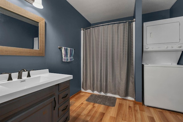 bathroom featuring wood-type flooring, vanity, and stacked washer and dryer