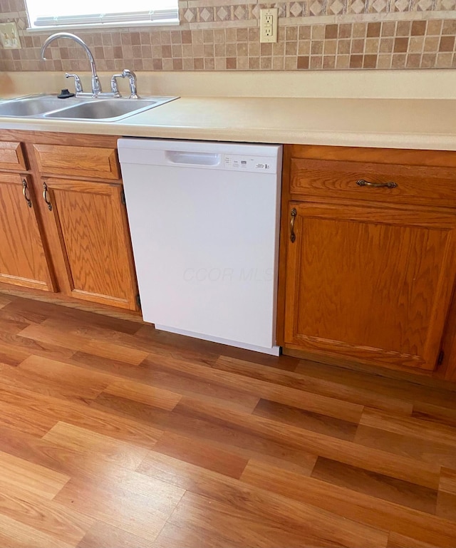 kitchen with a sink, brown cabinets, tasteful backsplash, and dishwasher