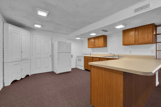 kitchen featuring visible vents, light countertops, a peninsula, white appliances, and a sink