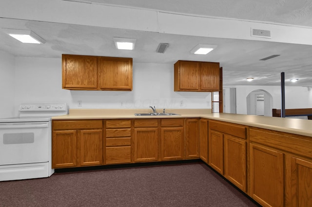 kitchen featuring brown cabinetry, visible vents, white range with electric cooktop, a sink, and light countertops