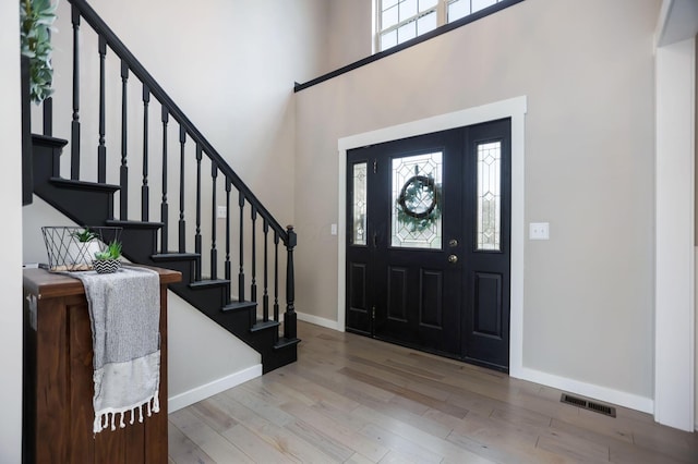 foyer entrance featuring a high ceiling, light hardwood / wood-style floors, and plenty of natural light